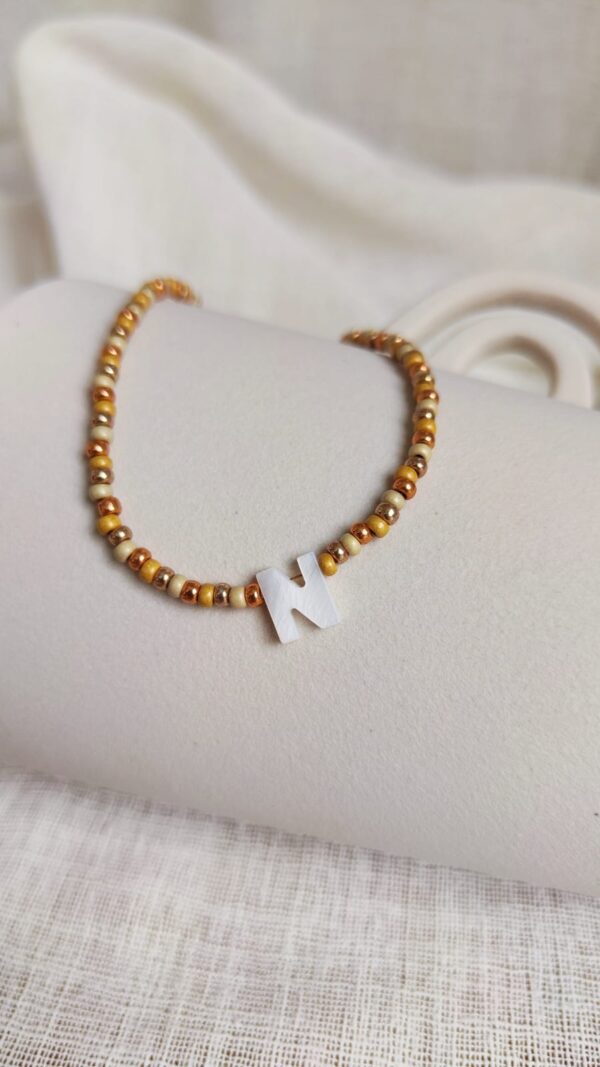 Collier Sand initiale avec perles dorées et champagne en Miyuki et lettre en nacre blanche élégante