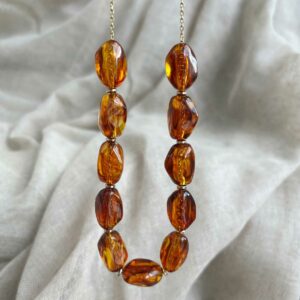 Collier Malibu Ambre composé de perles marbrées marron ambré aux reflets lumineux et finitions dorées.