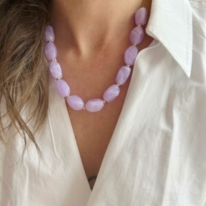 Close-up of a lavender marbled bead necklace with small gold spacers resting on a white shirt collarbone area.