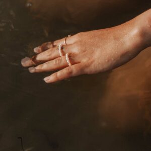 Bague élastique composée de véritables perles d'eau douce blanches portée à la main.