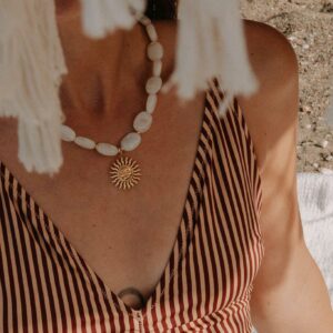 Collier Cadaquès avec perles marbrées blanc cassé et pendentif soleil en acier inoxydable.