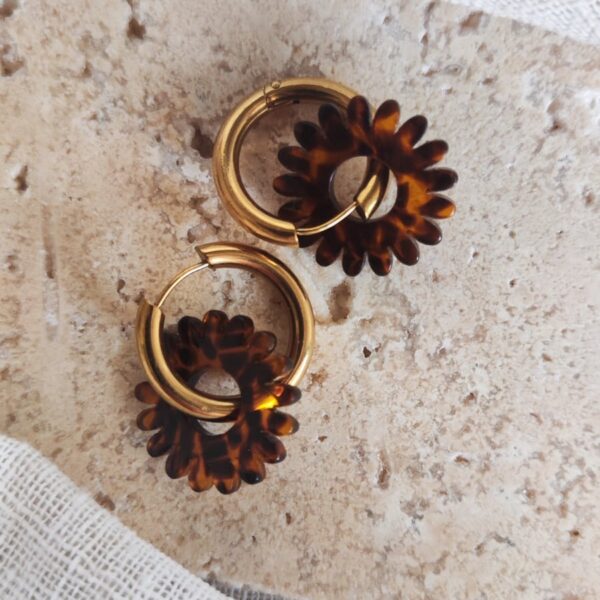 Créoles Milos en acier inoxydable doré avec pendentif fleur marguerite en acétate effet écaille marron.