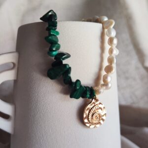 Beaded bracelet with green malachite chips and a row of white pearls, featuring a gold spiral shell charm.